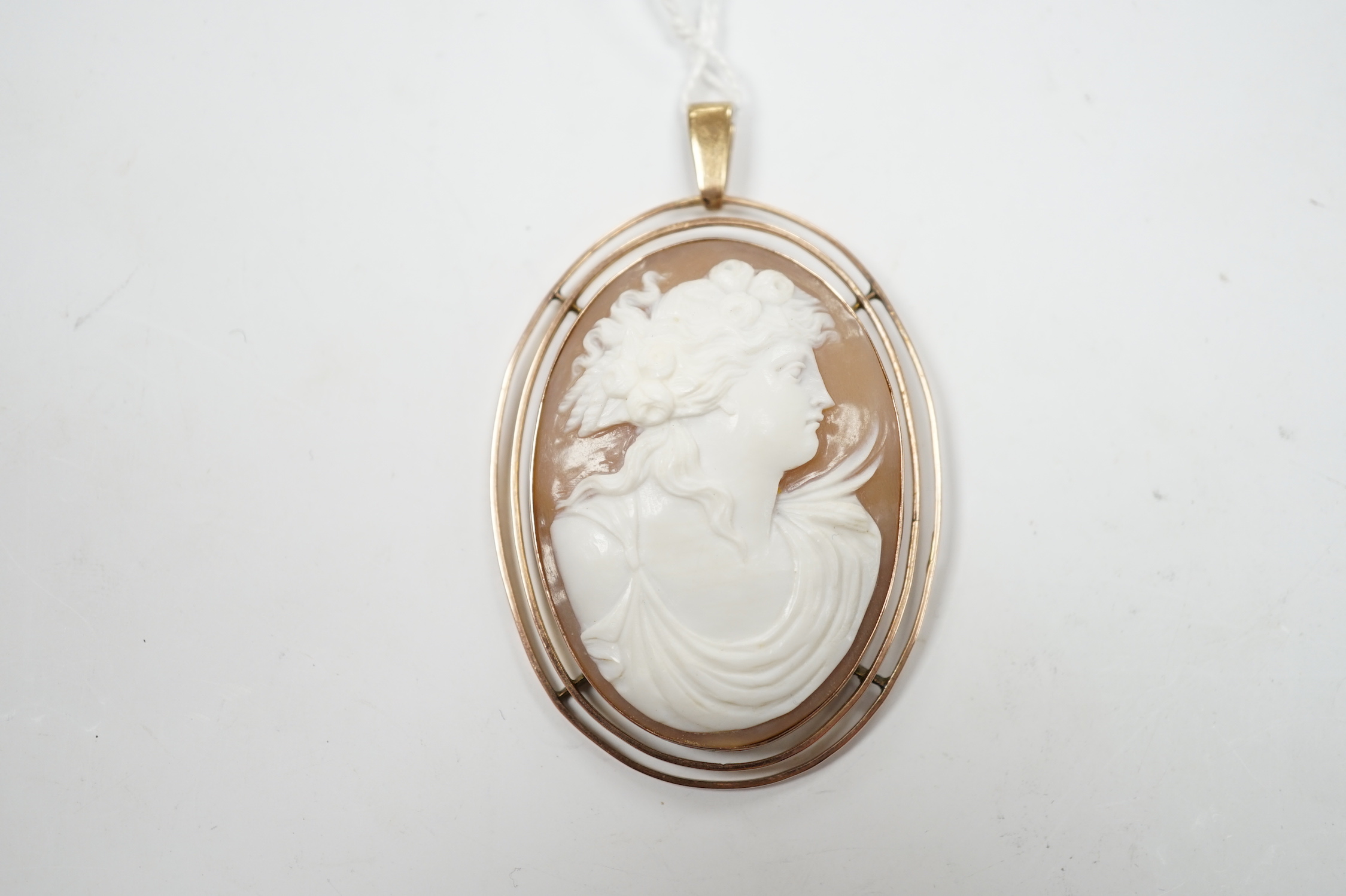 An early 20th century 9ct mounted oval cameo shell pendant, carved with the bust of a lady to sinister, overall 83mm, gross weight 13.2 grams.